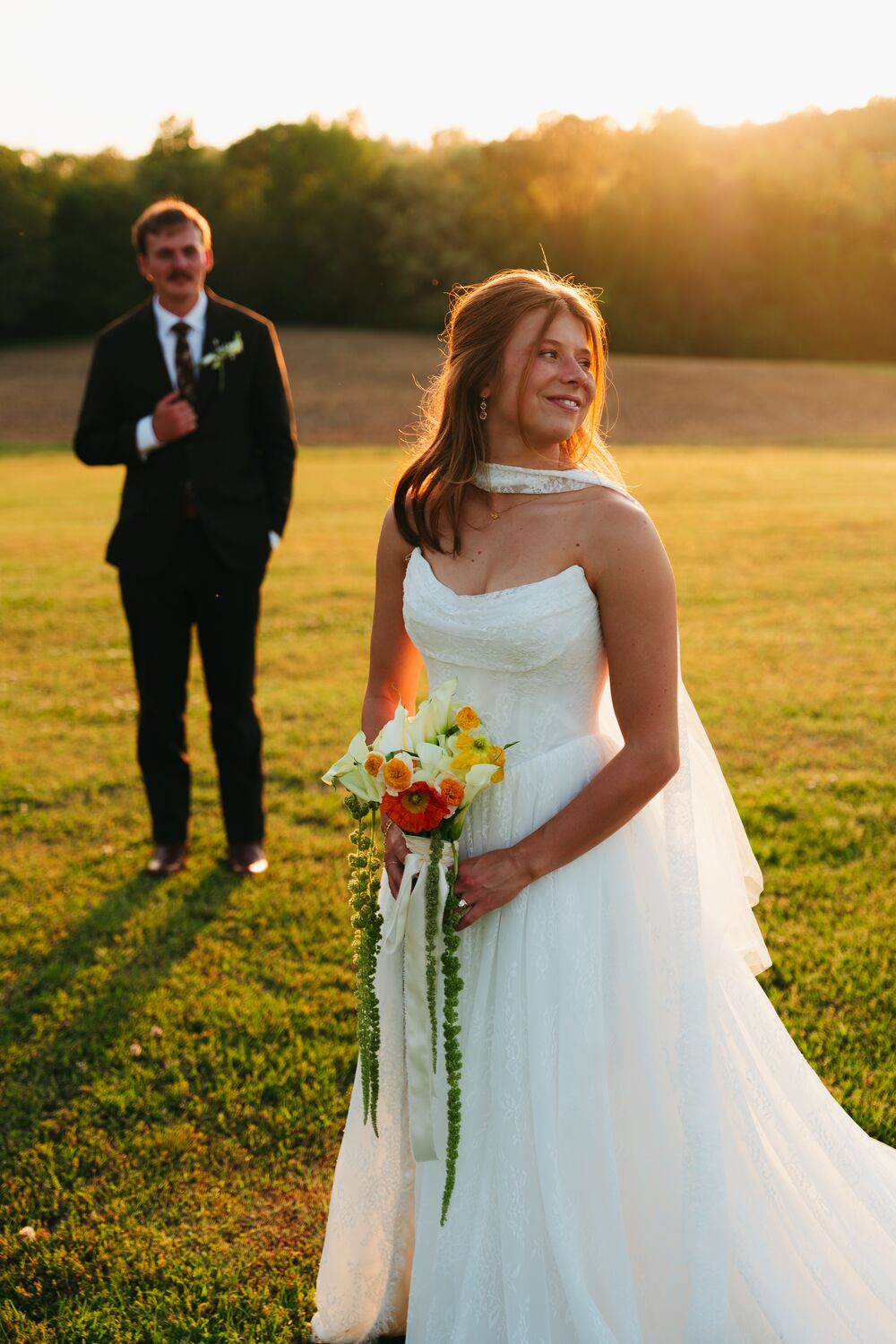 A bride and groom together in a golden-hour field