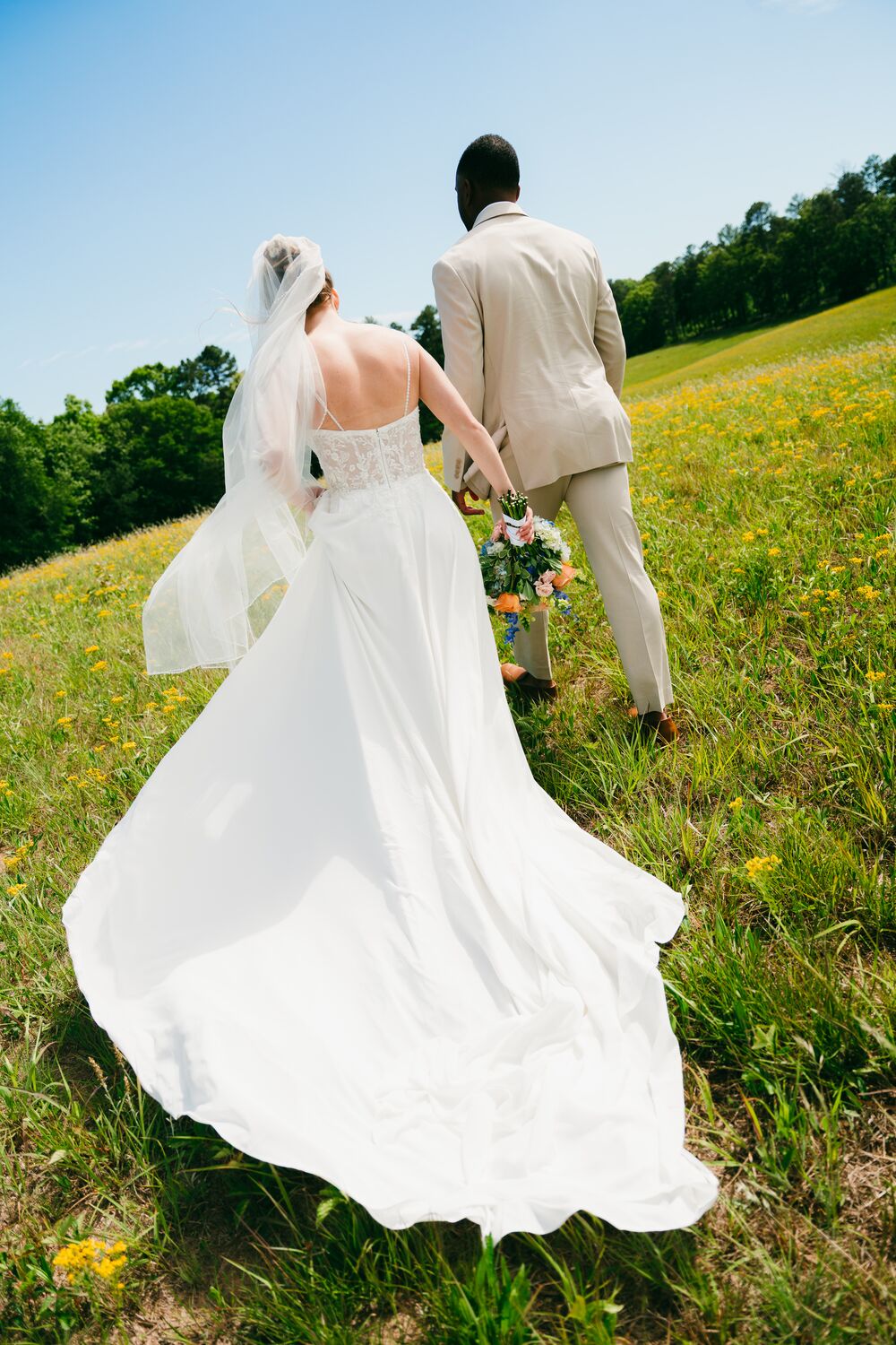 A couple walking away together through a sunlit field