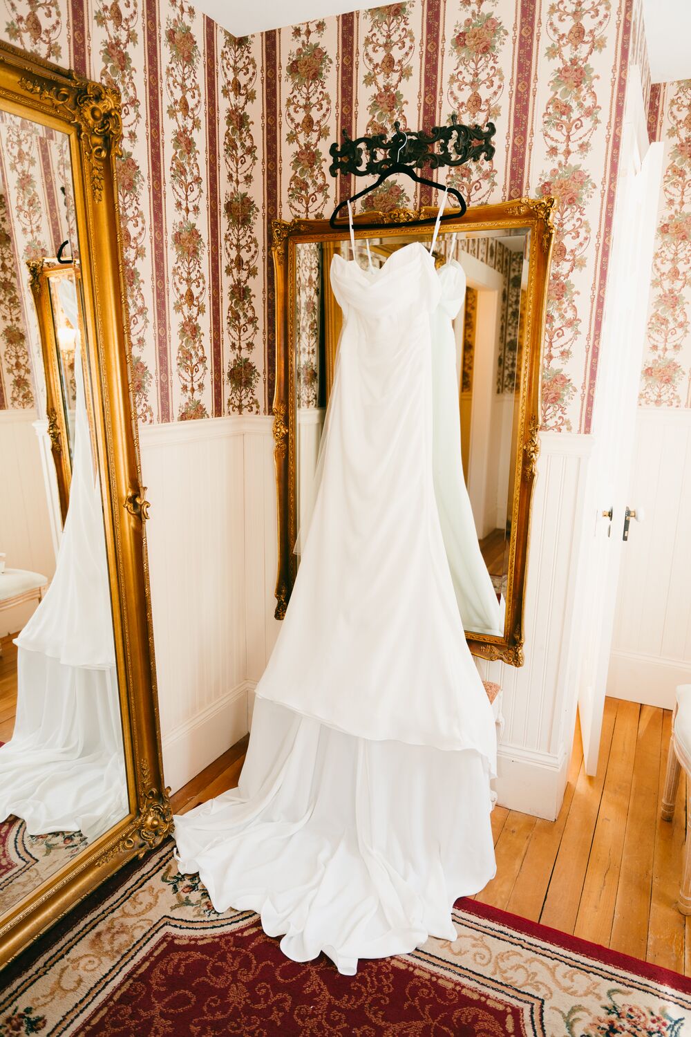 The gown hanging before a gilded mirror