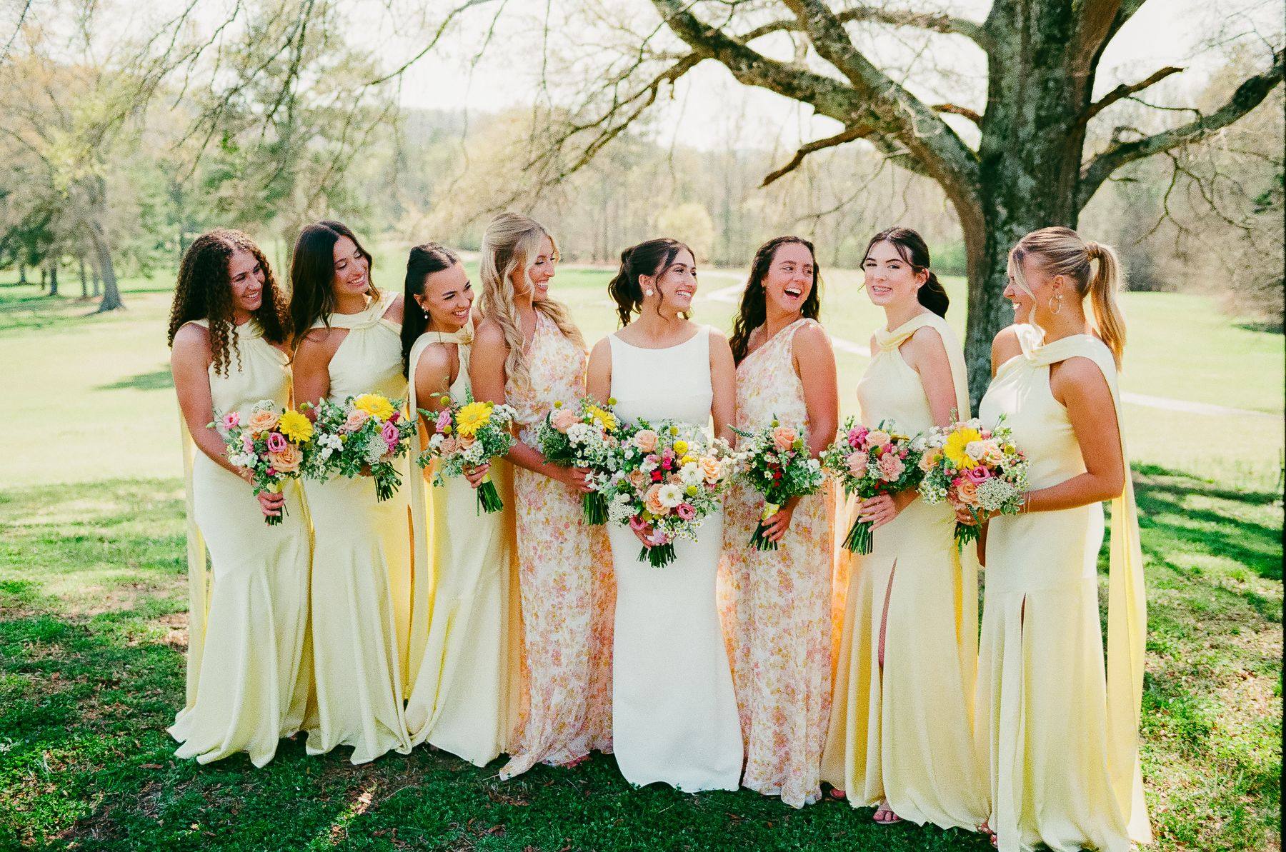 The bridesmaids in soft yellow laughing together, photographed on film