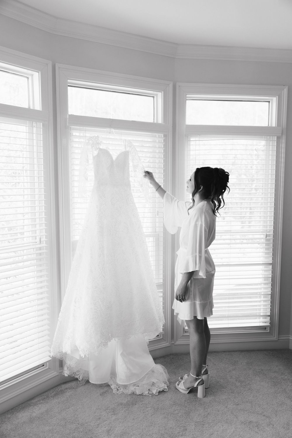 Eva reaching for her gown by the window, in black and white