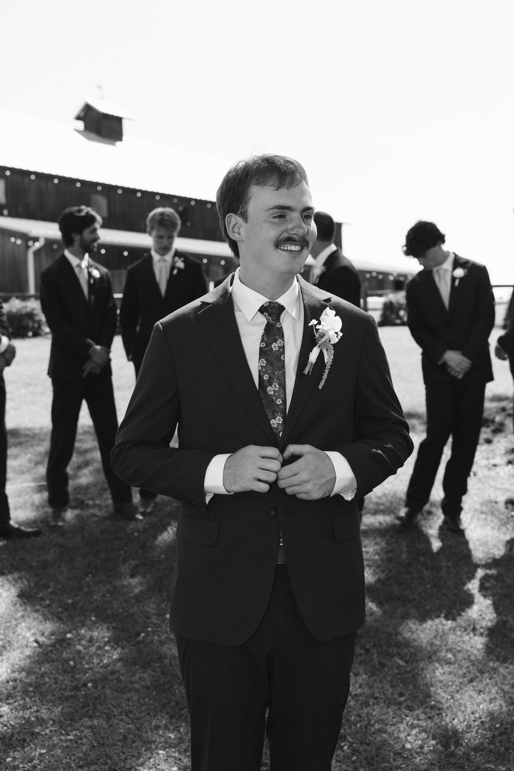 The groom grinning before the ceremony, in black and white