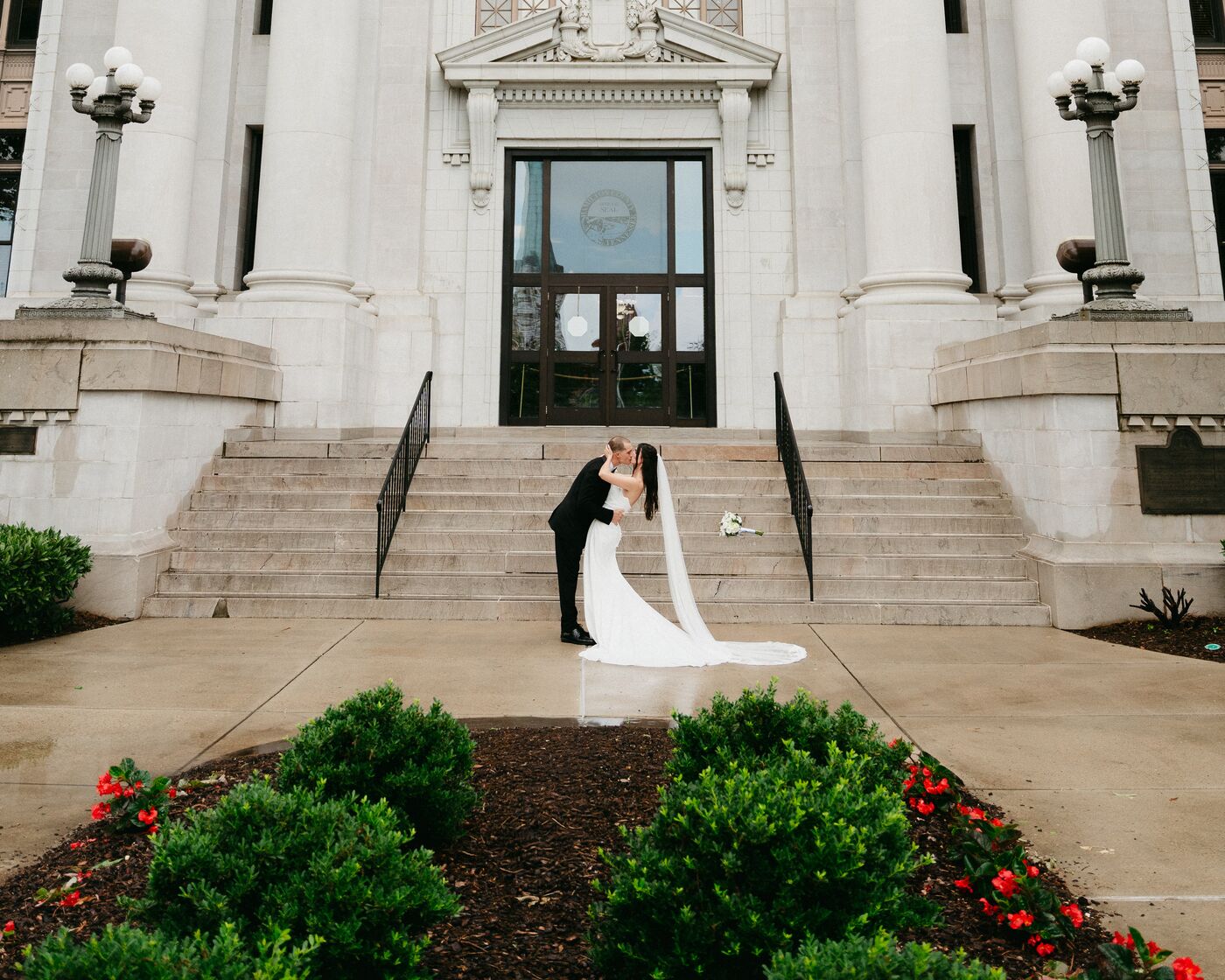 A newly married couple on the grand steps of a courthouse after their elopement