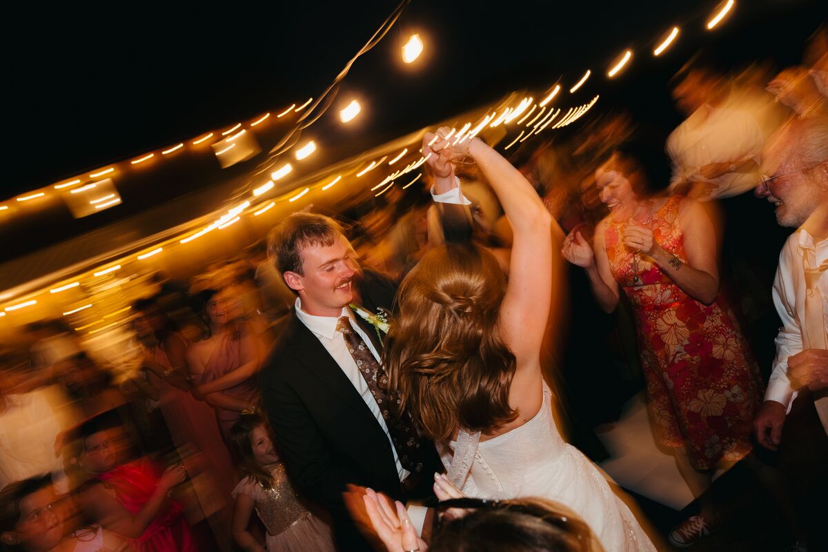 A bride and groom dancing under string lights, alive with motion